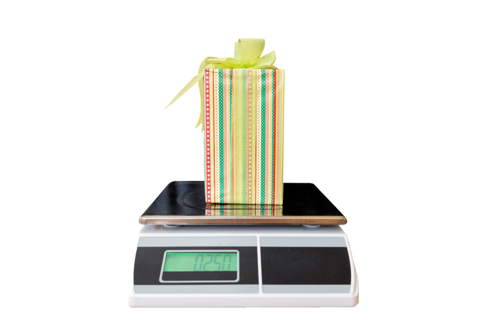 Electronic weighing scale displaying the weight of a colorful gift box on a digital screen